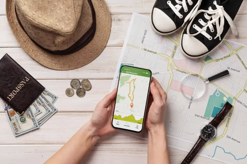 Imagem de um smartphone com um aplicativo de navegação, cercado por itens de viagem como uma roda, moedas, mapa, mochila e tênis, ideal para quem busca os 10 aplicativos indispensáveis para quem ama viajar e quer economizar tempo e dinheiro.